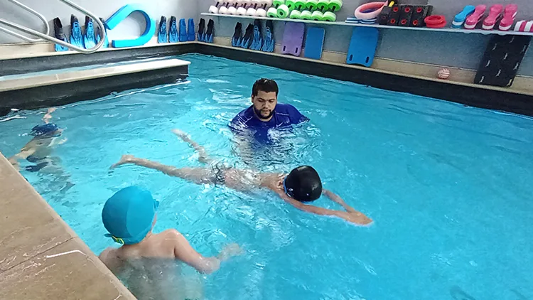 MNS donne un cours de natation dans un bassin à des enfants 5 ans