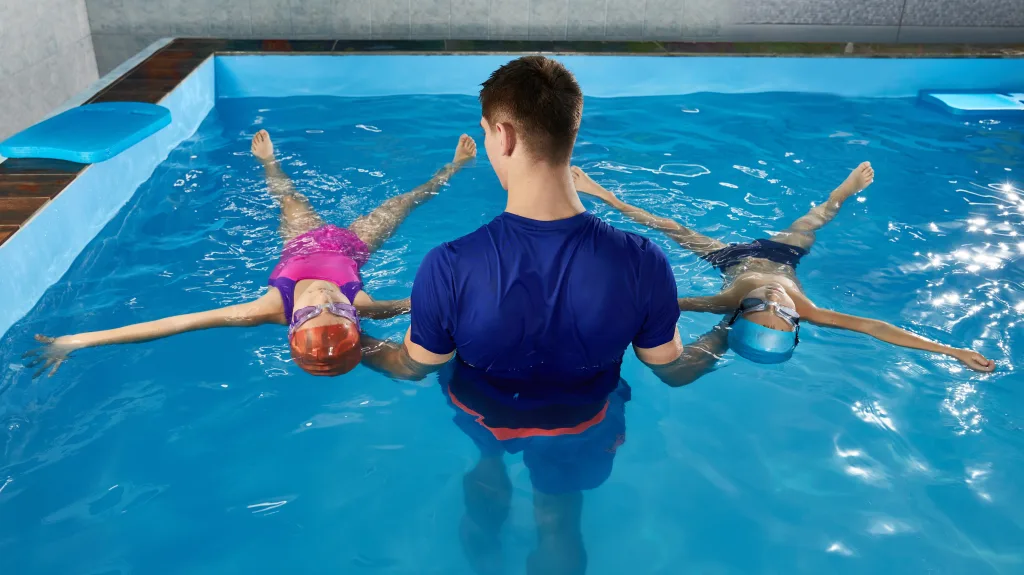 maitre nageur dans l'eau anime un cours de natation à des enfants