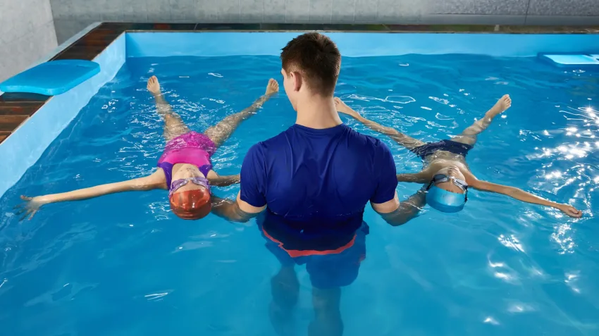maitre nageur dans l'eau anime un cours de natation à des enfants